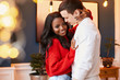 Happy young couple of different race in the interior of the Christmas hug each other standing in a stylish room. Black girl smiling with hands on man