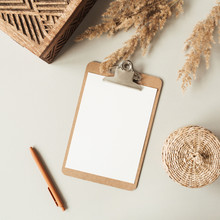 Blank Sheet Clipboard With Empty Copy Space, Pen, Rattan Casket On Neutral Background. Flat Lay, Top View Minimal Business Template For Social Media, Magazine, Blog. Home Office Desk Table Workspace.