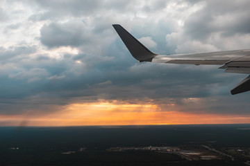 Airplane flying above the city at sunset.