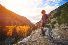 A Young Woman And Her Dog Hiking To The Top Of A Mountain