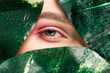 cropped view of girl with pink eyeshadow on eye with green leaves