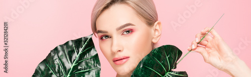 Fotomural panoramic shot of attractive girl with pink makeup isolated on pink with green l