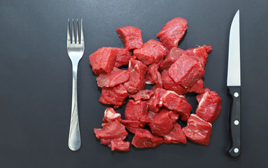 Raw red meat on black background.