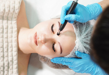 Microcurrent therapy for facial care. Cosmetologist doing face rejuvenation treatment.