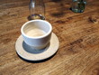 Weiße Kaffeetasse auf einem rustikalen braunen Holztisch in einem kleinen gemütlichen Café und Bistro in der Friedberger Landstraße im Nordend von Frankfurt am Main in Hessen