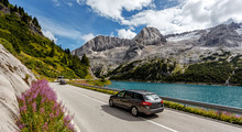 Awesome Alpine Highland In Sunny Day. Colorful Spring Scene. Summer View Of Asphalt Road Near Fedaia Lake And Marmolada Mountain.  Amazing Natural Scenery In Dolomites Alps. Picture Of Wild Area