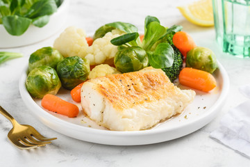 fried cod fillet with vegetables: baby carrots, brussels sprouts, broccoli, cauliflower and corn sal