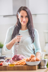 Wall Mural - Cheerful female cook in kitchen with joy and sharp knife preparing lunch