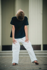 the boy is engaged in capoeira on the street