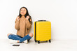 © Asier - Young chinese traveler woman sittting on the floor with a suitcase isolated raising fist, feeling happy and successful. Victory concept.