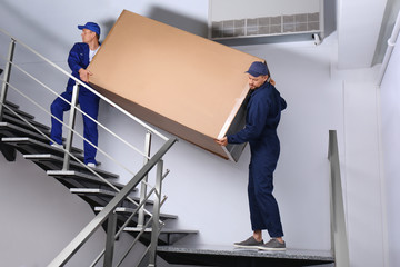 Wall Mural - Professional workers carrying refrigerator on stairs indoors