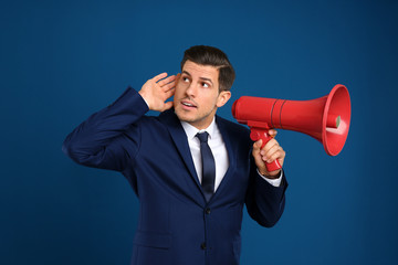 Handsome man with megaphone on blue background