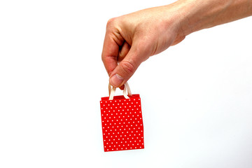 Male hand holding red gift bag isolated on white background. Minimalistic concept.