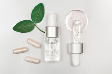 Wall Mural - Bottle with hyaluronic acid on silver background. Concept of modern beauty. Flat lay style.