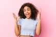 Young african american woman against a pink background receiving a pleasant surprise, excited and raising hands.