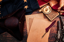 Federalist Papers And The Birth Of The United States Of America Concept With Tricorn Hat, Candle, Feather Quill, Musket Gun, The Betsy Ross American Flag And Aged Paper With Copy Space