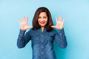 Middle age latin woman isolated on a blue background showing number ten with hands.