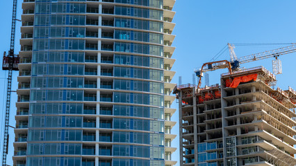 Modern building being constructed. Cranes and scaffolding equipment on site.