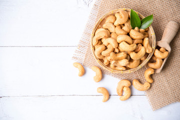 Wall Mural - Roasted salted raw cashew nuts with Fresh cashew in spoon and  basket isolated on white wooden background.