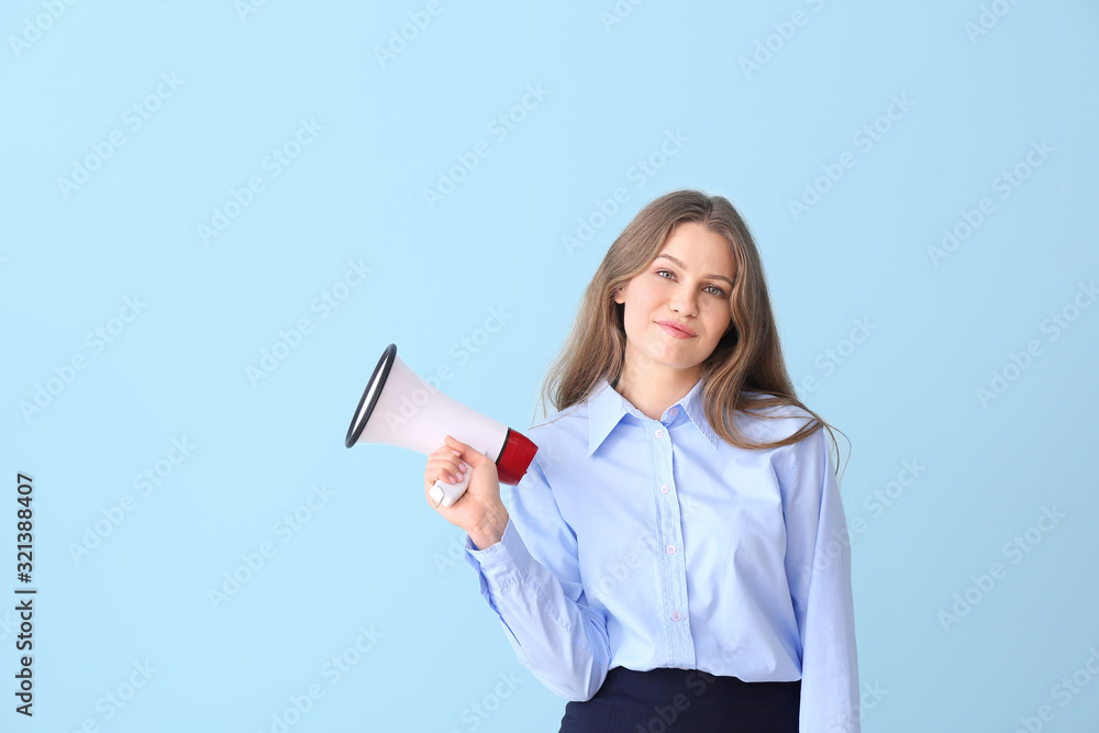 Young businesswoman with megaphone on color background