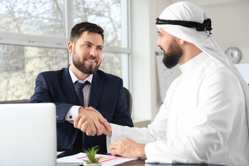 Wall Mural - Arab man and his business partner shaking hands in office