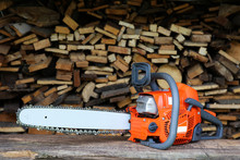  Chainsaw Is On Sawn Firewood Background.