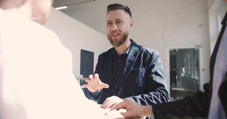 Handsome successful middle aged businessman talking to young millennial partners at comfortable light modern loft office