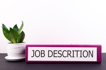job descrition inscription on the office folder on a dark desktop with a flower in a flowerpot on a 