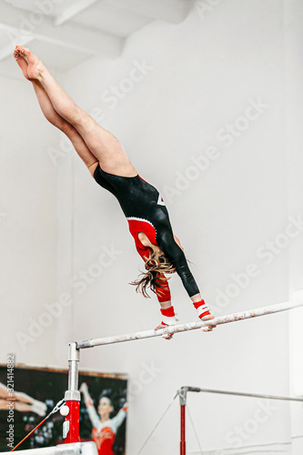 Fotografía young woman gymnast exercise on uneven bars in gymnastics