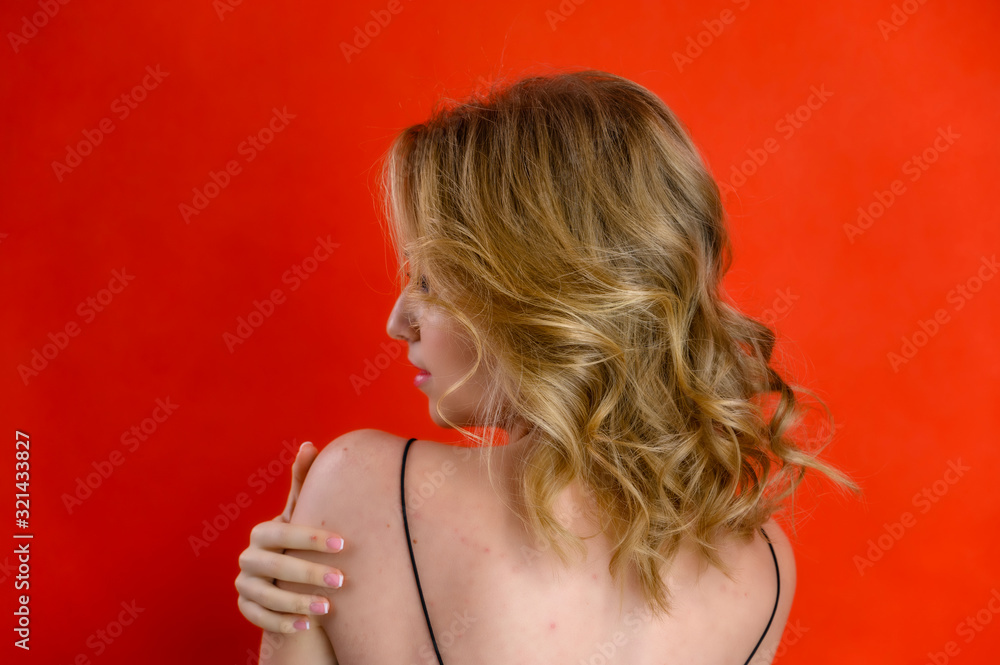 The concept of cosmetics, fashion and style. Glamorous beauty rear view portrait of a pretty model with blond hair with great makeup and a beautiful hairstyle on a red background in the studio. - obrazy, fototapety, plakaty 