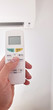© astrosystem - Modern airconditioner unit with a hand holding a remote.