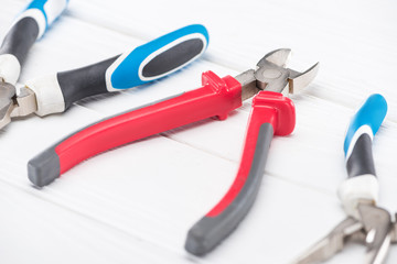 Wall Mural - Selective focus of pliers on white wooden background