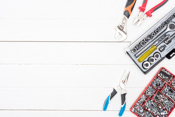 Wall Mural - Top view of tool boxes with wrenches, bolts and nuts pliers on white wooden surface