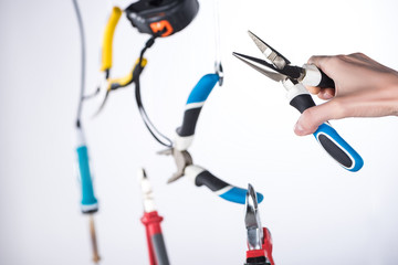 Wall Mural - Cropped view of man holding pliers with levitating tools in air isolated on grey