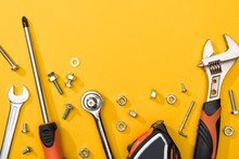 Top View Of Tool Set With Nuts And Bolts On Yellow Background