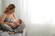 Young woman breastfeeding her baby at home. Space for text