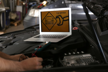 Poster - Mechanic with laptop doing car diagnostic at automobile repair shop, closeup