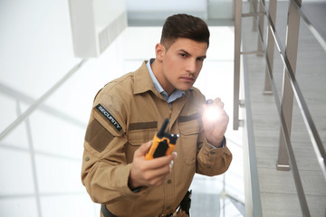 Wall Mural - Professional security guard with portable radio set and flashlight on stairs