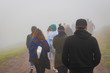 Back view of refugees walk to the border in a cold day under fog