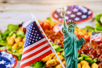 Statue of Liberty and american flag on party table with food not in focuse..