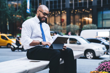 Wall Mural - Black excited manager typing on tablet on street