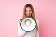 © luismolinero - Young blonde woman over isolated pink background shouting through a megaphone