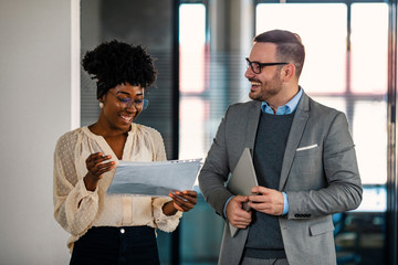 Business colleagues interacting with each other while walking in the corridor. A businessman who is discussing a job with his female co-worker By consulting about the work in the office