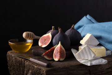 Wall Mural - Fresh ripe figs. Breakfast with figs, cheese, honey and nuts. A few figs on an old wooden background. Whole figs and one fig sliced. Fresh fruits, purple figs on the wooden background. Autumn harvest.