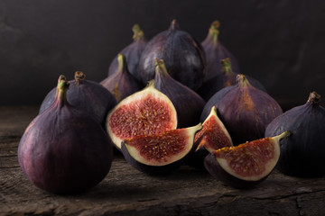 Wall Mural - Fresh ripe figs. A few figs on an old wooden background. Whole figs and one fig sliced. Fresh fruits, purple figs on the wooden background. Autumn harvest. Free space for text. Free space for text. Da