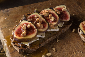 Wall Mural - Figs. Sandwiches with figs, cheese, arugula, honey and nuts. toast with creamy yogurt and feta cheese spread, fresh figs with honey. Bruschetta with cheese and figs. Homemade. Everyday autumn kitchen.