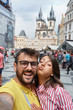 © luckybusiness - Man and woman walking in city streets on vacation tourism and making selfie.