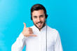 Telemarketer man working with a headset over isolated blue background making phone gesture