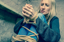 Blonde Girl With Her Hands And Feet Tied Is Sitting In The Basement. Concept Of Kidnapping, Violence