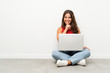© luismolinero - Young woman with a laptop sitting on the floor doing silence gesture